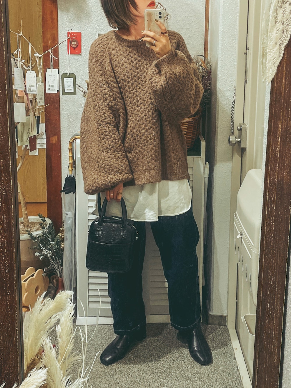 ブラウン系のニット/セーター、ホワイト系のTシャツ/カットソー、ブルー系のデニムパンツを着用したレディースの冬コーディネートの1枚目の写真