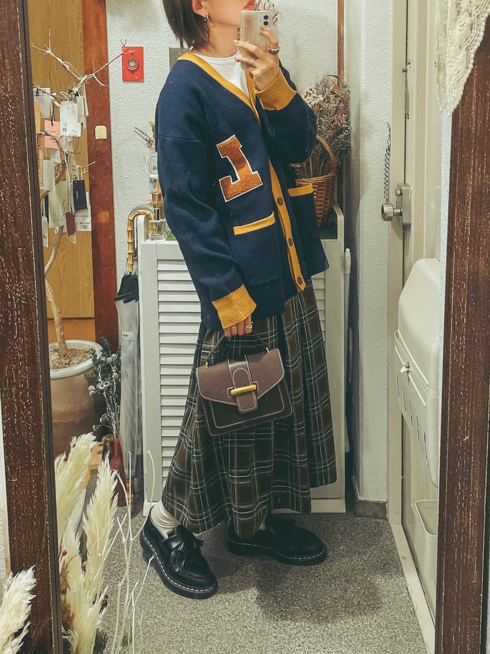 ブラウン系のショルダーバッグ、ブルー系のカーディガン/ボレロ、ブラウン系のスカートを着用したレディースの冬コーディネートの1枚目の写真