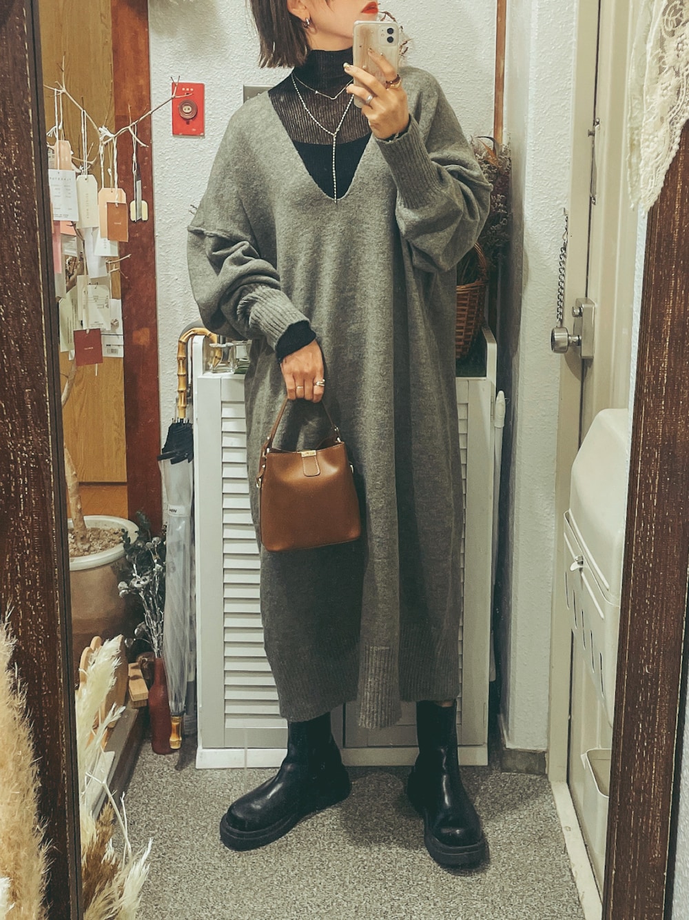 ブラウン系のショルダーバッグ、グレー系のワンピース、ブラック系のブーツを着用したレディースの冬コーディネートの1枚目の写真