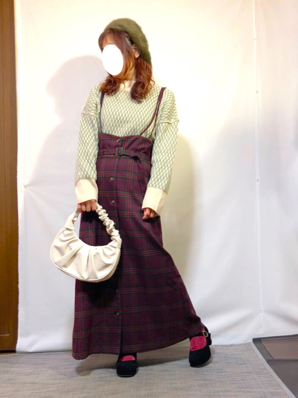 グリーン系のニット/セーター、レッド系のジャンパースカート、ブラック系のパンプスを着用したレディースの冬コーディネートの1枚目の写真