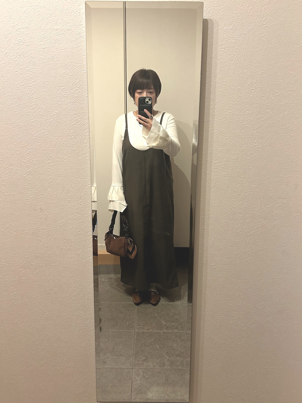 ブラウン系のパンプス、ブラウン系のハンドバッグを着用したレディースの秋コーディネートの1枚目の写真