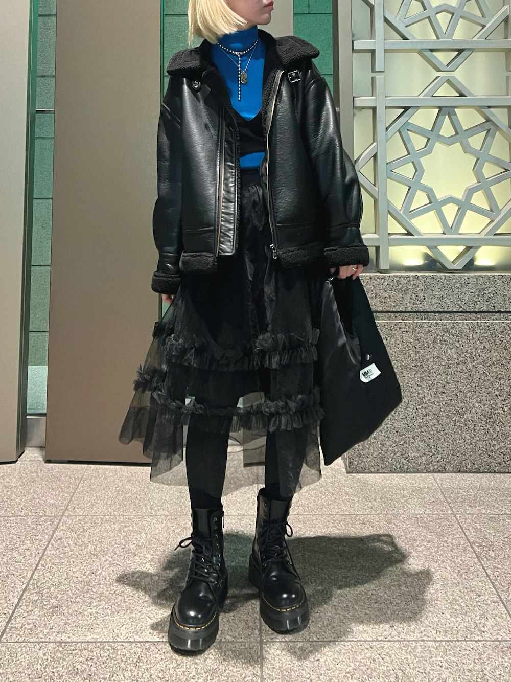 ブラック系のつなぎ/オールインワン、ブルー系のニット/セーター、ブラック系のムートンコートを着用したレディースの春コーディネートの1枚目の写真