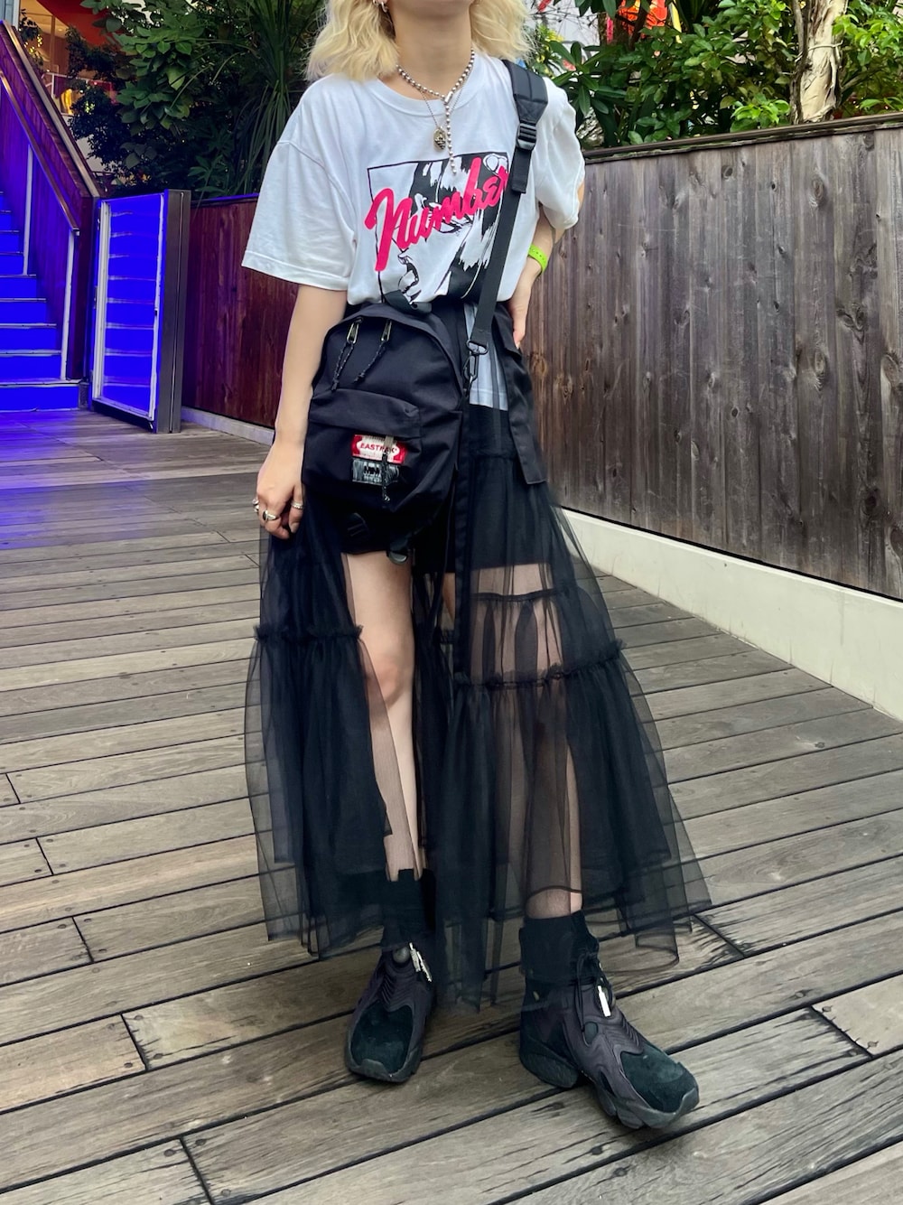 ブラック系のスカート、ブラック系のスニーカー、ブラック系のバックパック/リュックを着用したレディースの秋コーディネートの1枚目の写真