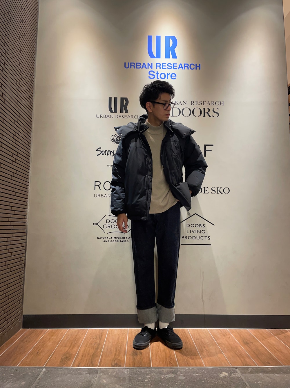 ブラック系のダウンジャケット/コート、ベージュ系のニット/セーター、ブルー系のデニムパンツを着用したメンズの冬コーディネートの1枚目の写真