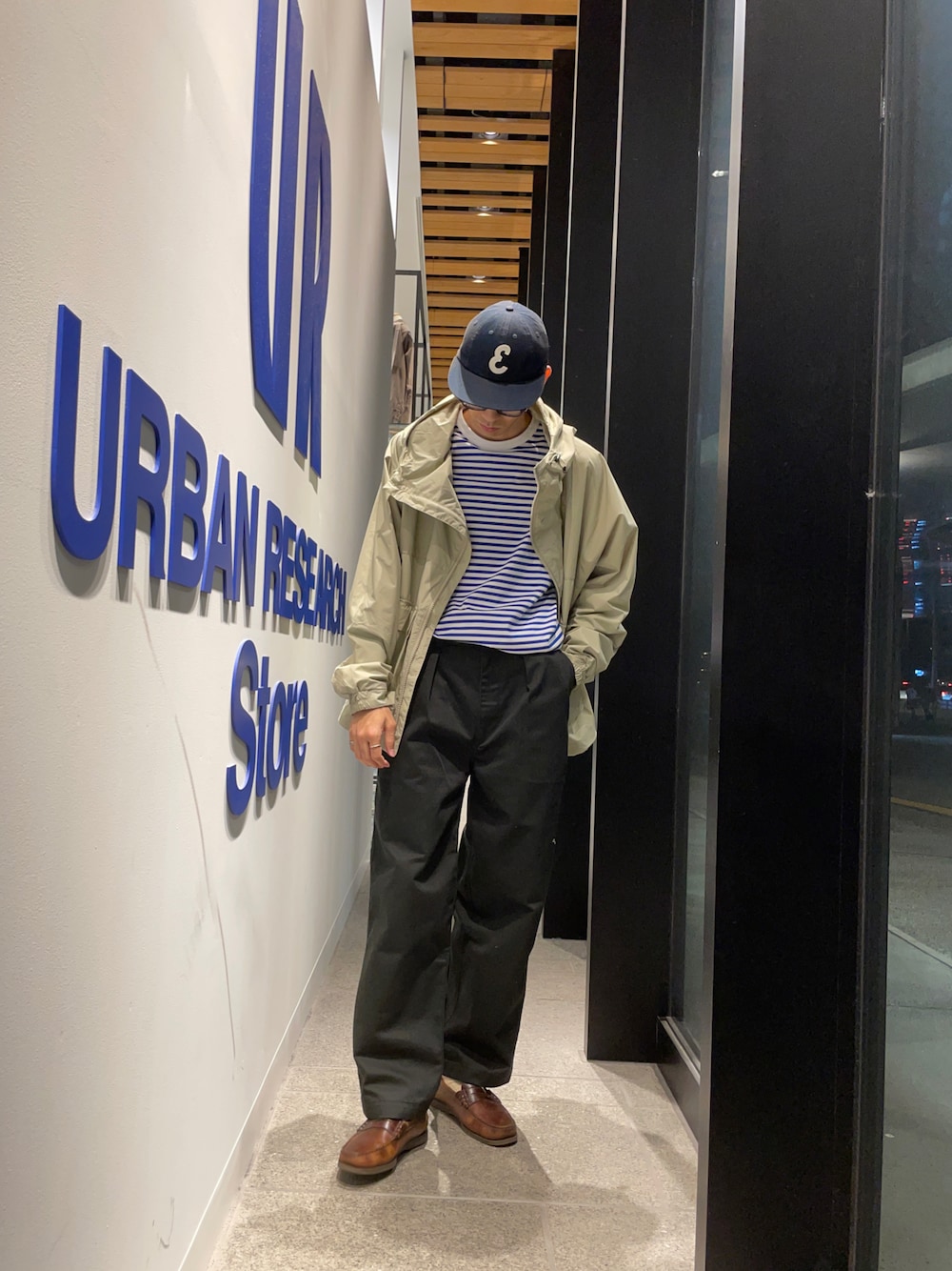 ブラック系のチノパンツ、グリーン系のナイロンジャケット、ブルー系のTシャツ/カットソーを着用したメンズの秋コーディネートの1枚目の写真