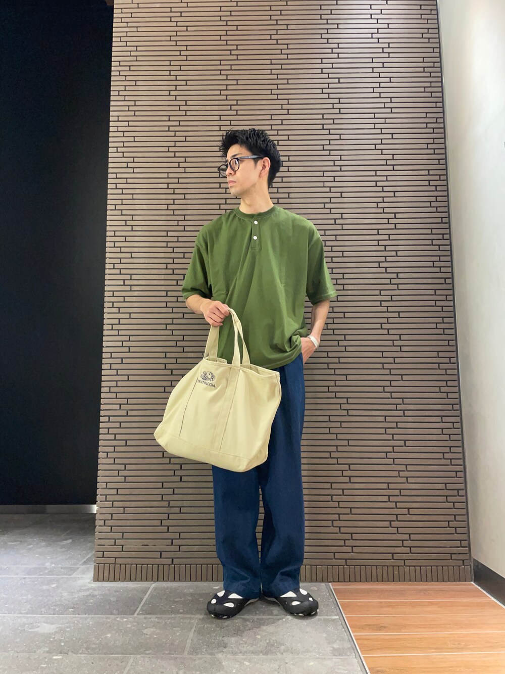 グリーン系のTシャツ/カットソー、ベージュ系のトートバッグ、ブルー系のデニムパンツを着用したメンズの夏コーディネートの1枚目の写真