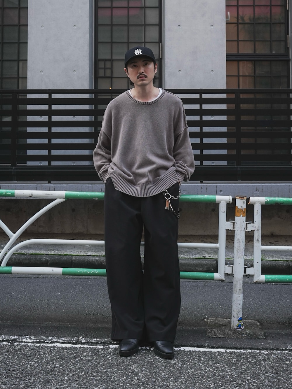 グレー系のニット/セーター、ブラック系のスラックスを着用したメンズの秋コーディネートの1枚目の写真