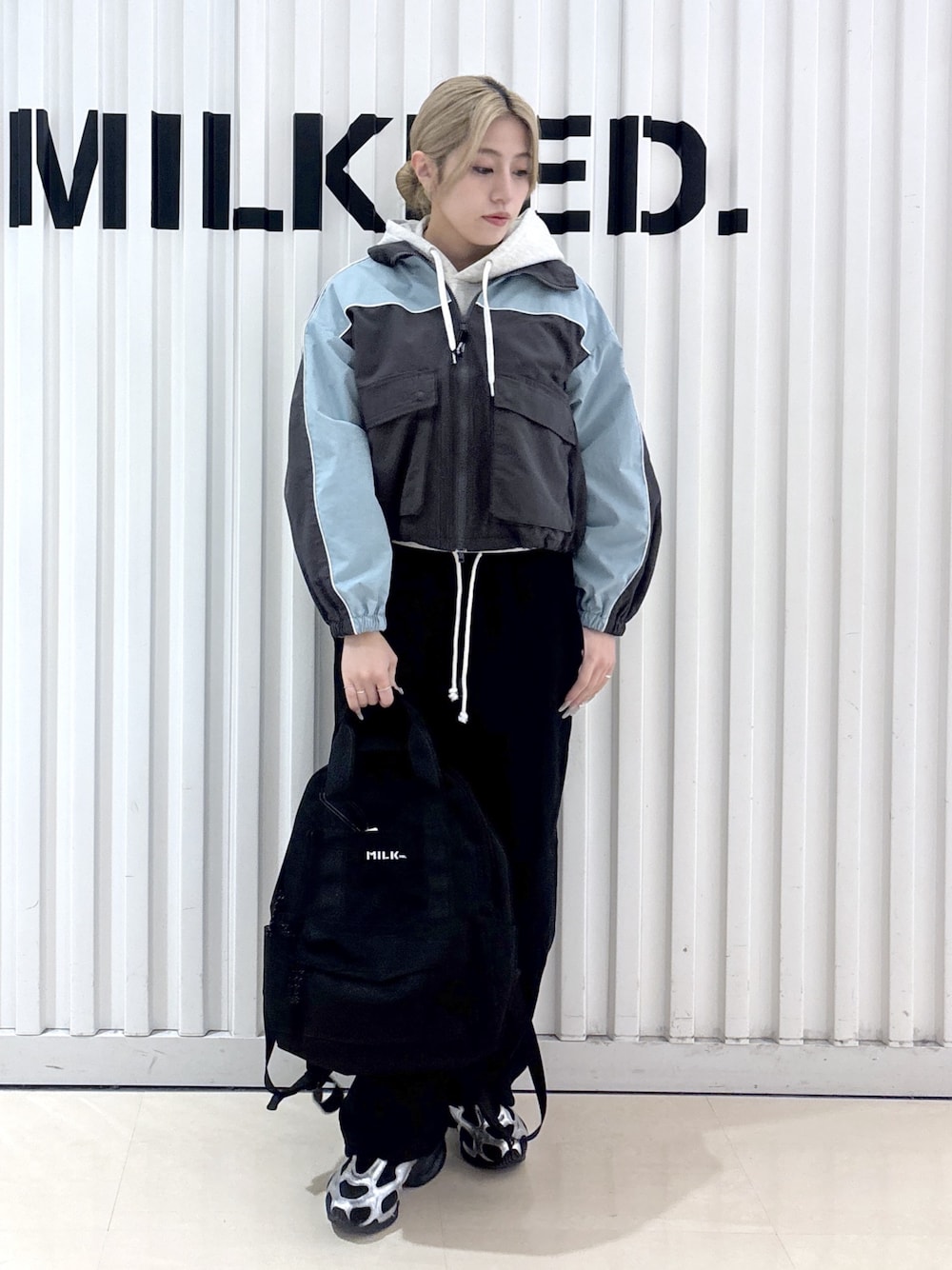 グレー系のナイロンジャケット、ベージュ系のパーカー、ブラック系のスウェットパンツを着用したレディースの春コーディネートの1枚目の写真