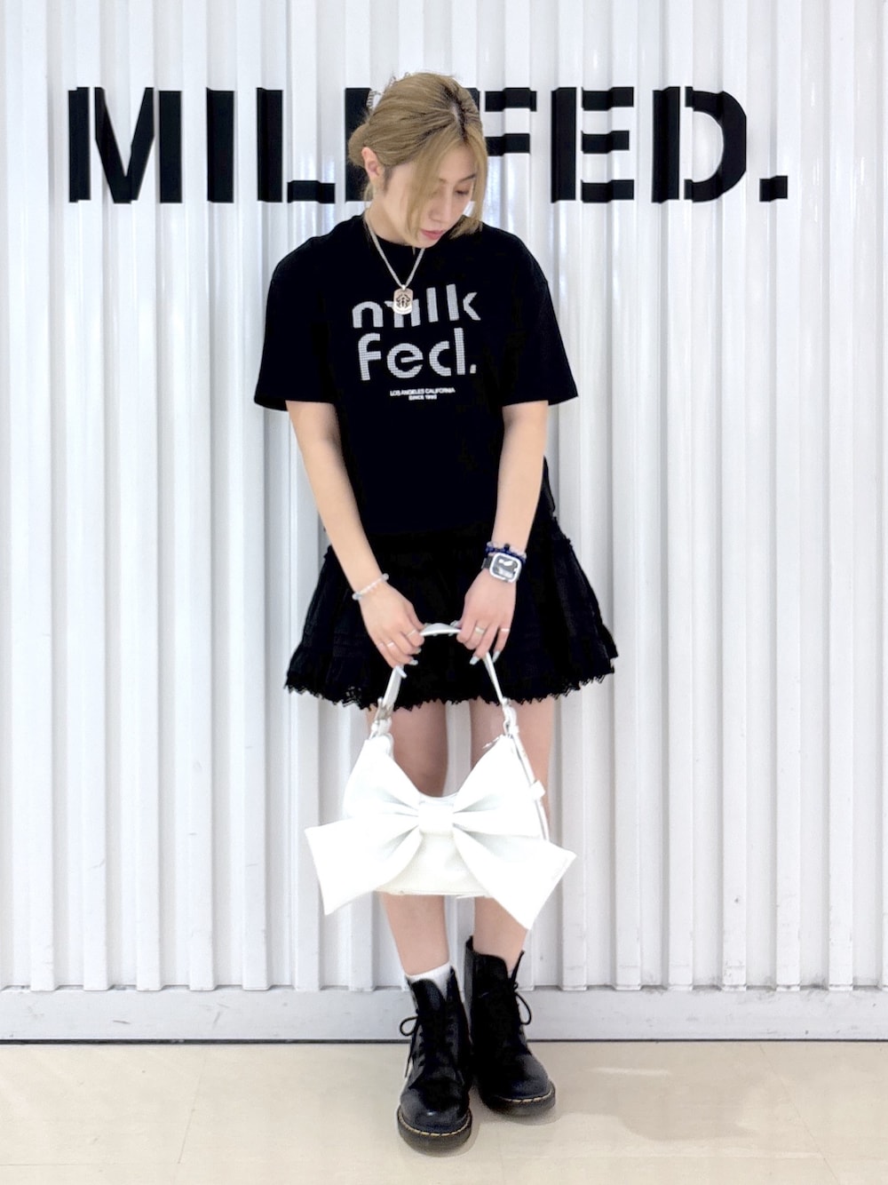 ブラック系のTシャツ/カットソー、ブラック系のスカート、ホワイト系のショルダーバッグを着用したレディースの春コーディネートの1枚目の写真