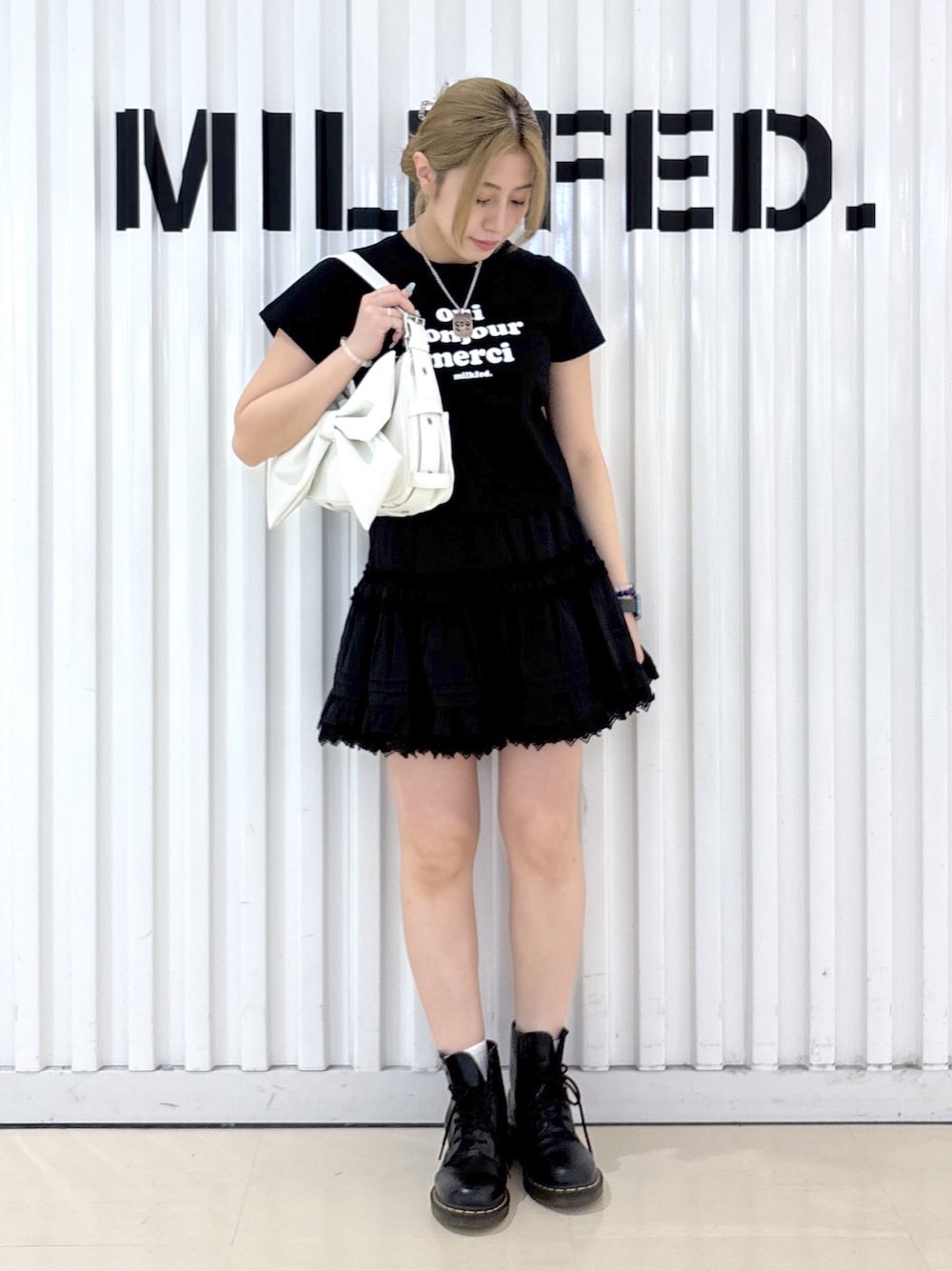 ホワイト系のショルダーバッグ、ブラック系のスカート、ブラック系のTシャツ/カットソーを着用したレディースの夏コーディネートの1枚目の写真