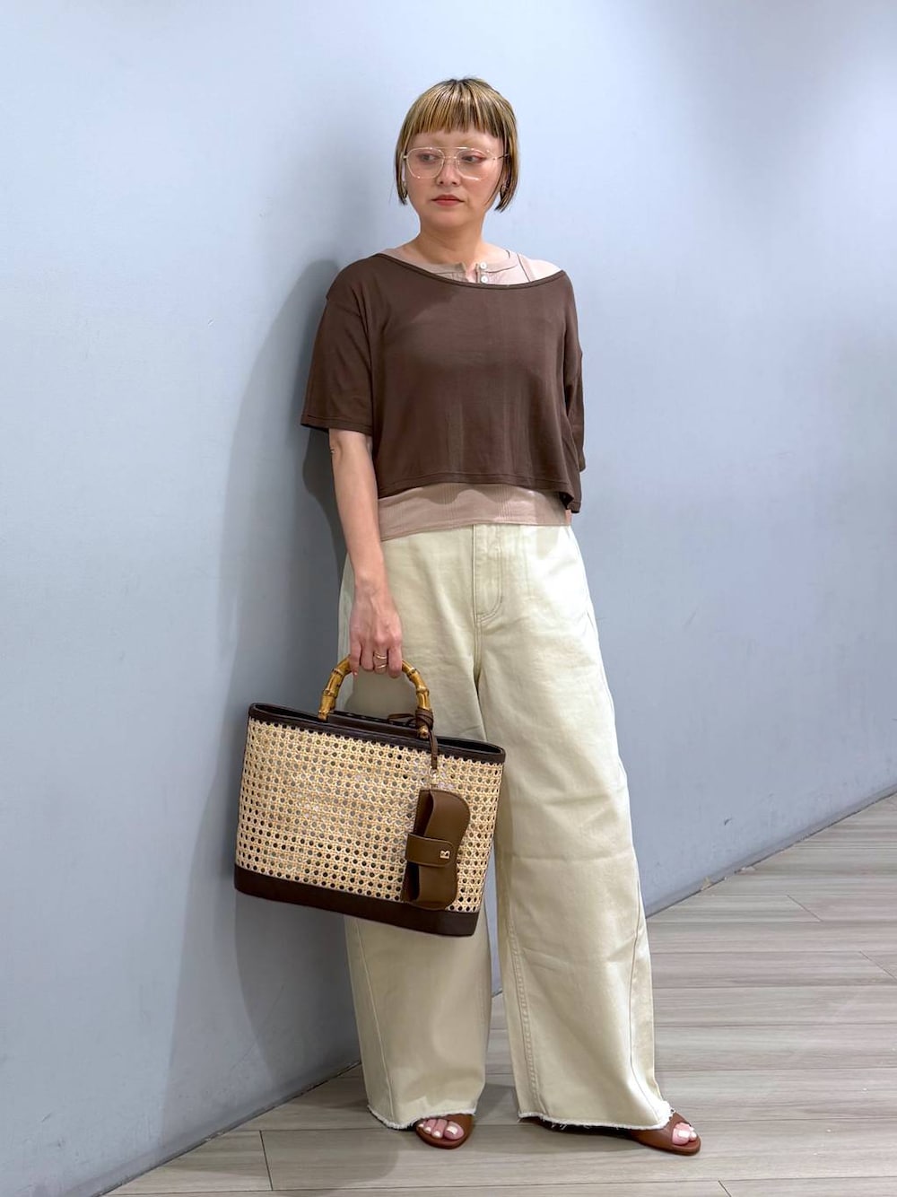 ベージュ系のデニムパンツ、ブラウン系のアンサンブル、ベージュ系のかごバッグを着用したレディースの春コーディネートの1枚目の写真