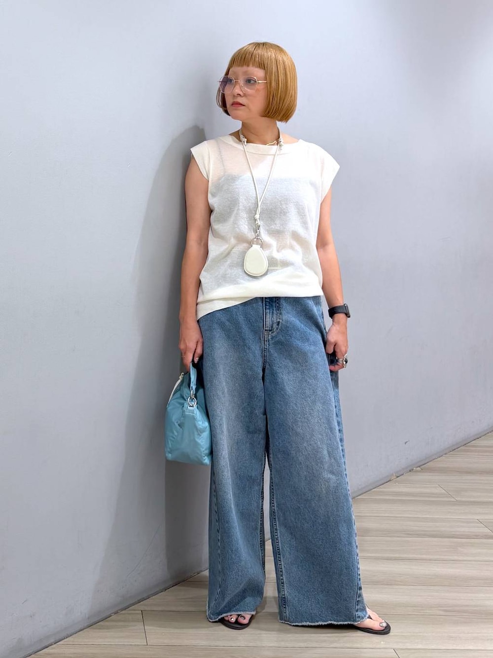 ブルー系のデニムパンツ、ホワイト系のTシャツ/カットソー、ブルー系のハンドバッグを着用したレディースの夏コーディネートの1枚目の写真