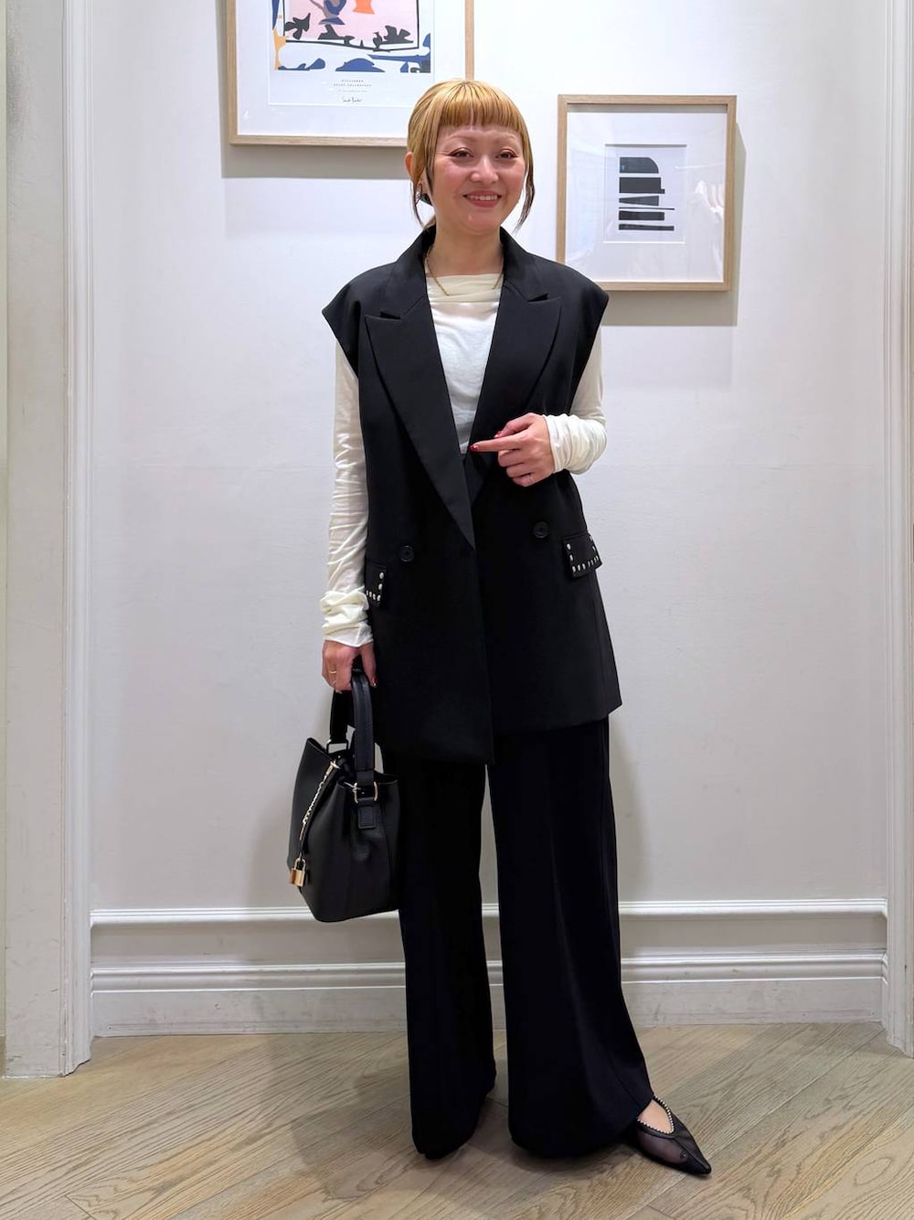 ブラック系のベスト、ブラック系のスラックス、ホワイト系のTシャツ/カットソーを着用したレディースの冬コーディネートの1枚目の写真