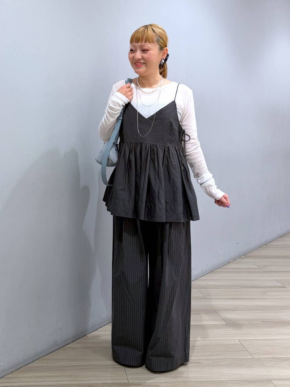 ブルー系のハンドバッグ、ホワイト系のTシャツ/カットソー、グレー系のキャミソールを着用したレディースの冬コーディネートの1枚目の写真