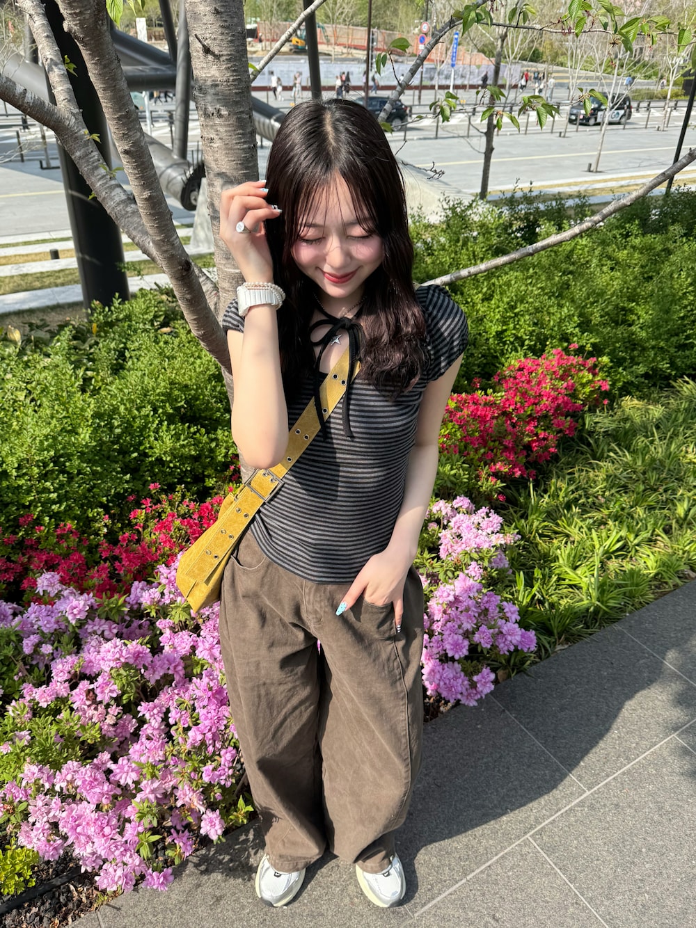 イエロー系のショルダーバッグ、ホワイト系のスニーカー、ブラウン系のデニムパンツを着用したレディースの春コーディネートの1枚目の写真