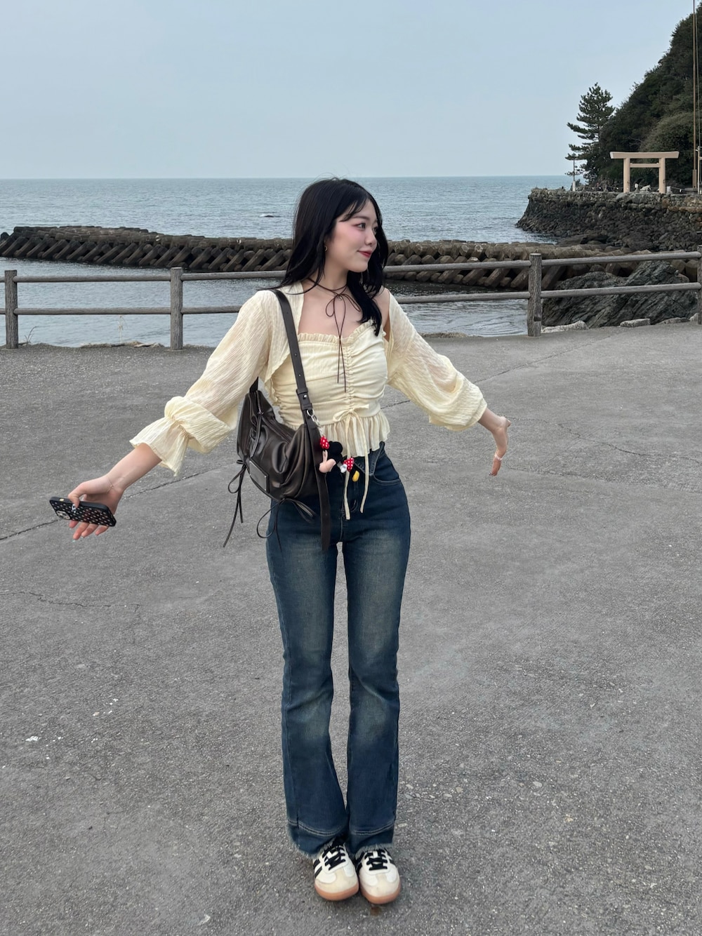 ブラウン系のハンドバッグ、ブルー系のデニムパンツ、イエロー系のTシャツ/カットソーを着用したレディースの春コーディネートの1枚目の写真