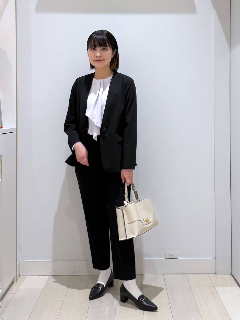 ブラック系のスラックス、パープル系のシャツ/ブラウス、ブラック系のノーカラージャケットを着用したレディースの春コーディネートの1枚目の写真