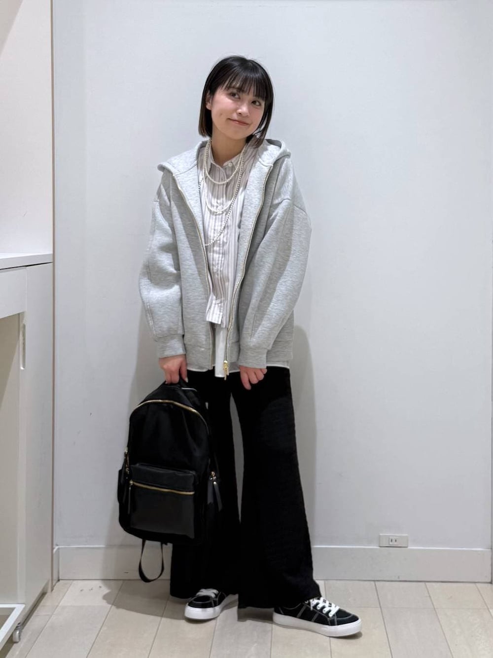 ブラック系のバックパック/リュック、グレー系のパーカー、ホワイト系のタンクトップを着用したレディースの春コーディネートの1枚目の写真