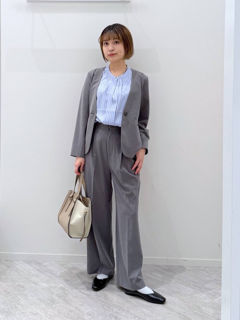 ブラック系のパンプス、ベージュ系のショルダーバッグ、ブルー系のシャツ/ブラウスを着用したレディースの春コーディネートの1枚目の写真