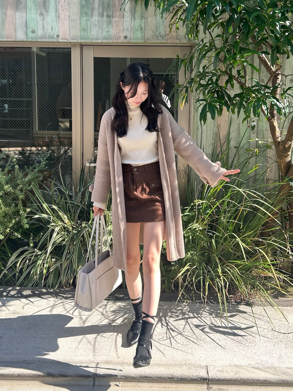 ブラウン系のスカート、ホワイト系のカーディガン/ボレロを着用したレディースの秋コーディネートの1枚目の写真