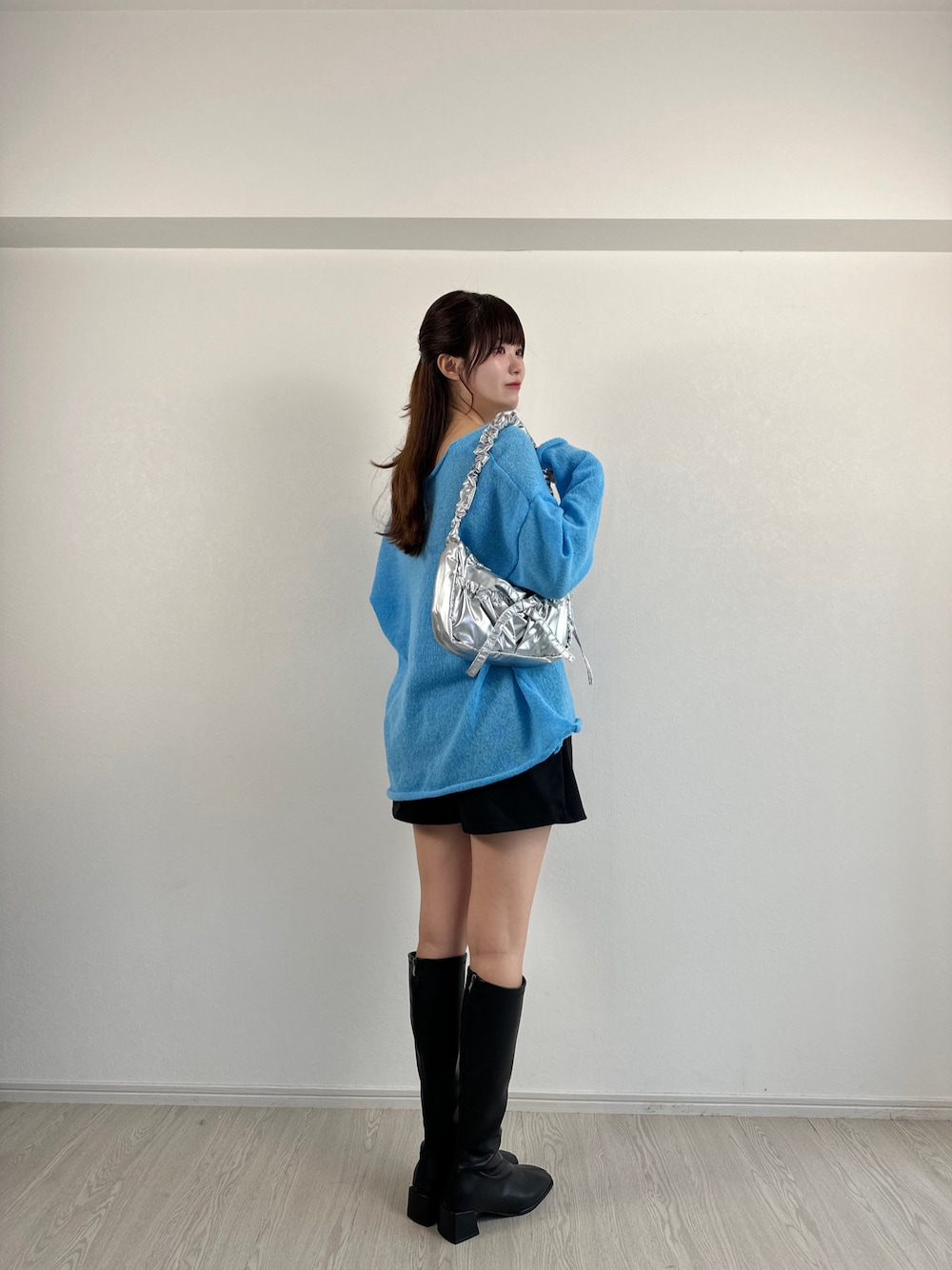 ブルー系のニット/セーター、ブラック系のその他パンツ、シルバー系のハンドバッグを着用したレディースの秋コーディネートの1枚目の写真