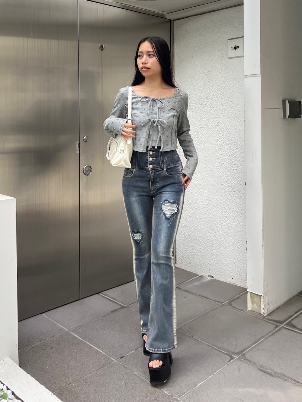 グレー系のTシャツ/カットソー、ブルー系のデニムパンツ、ホワイト系のハンドバッグを着用したレディースの夏コーディネートの1枚目の写真