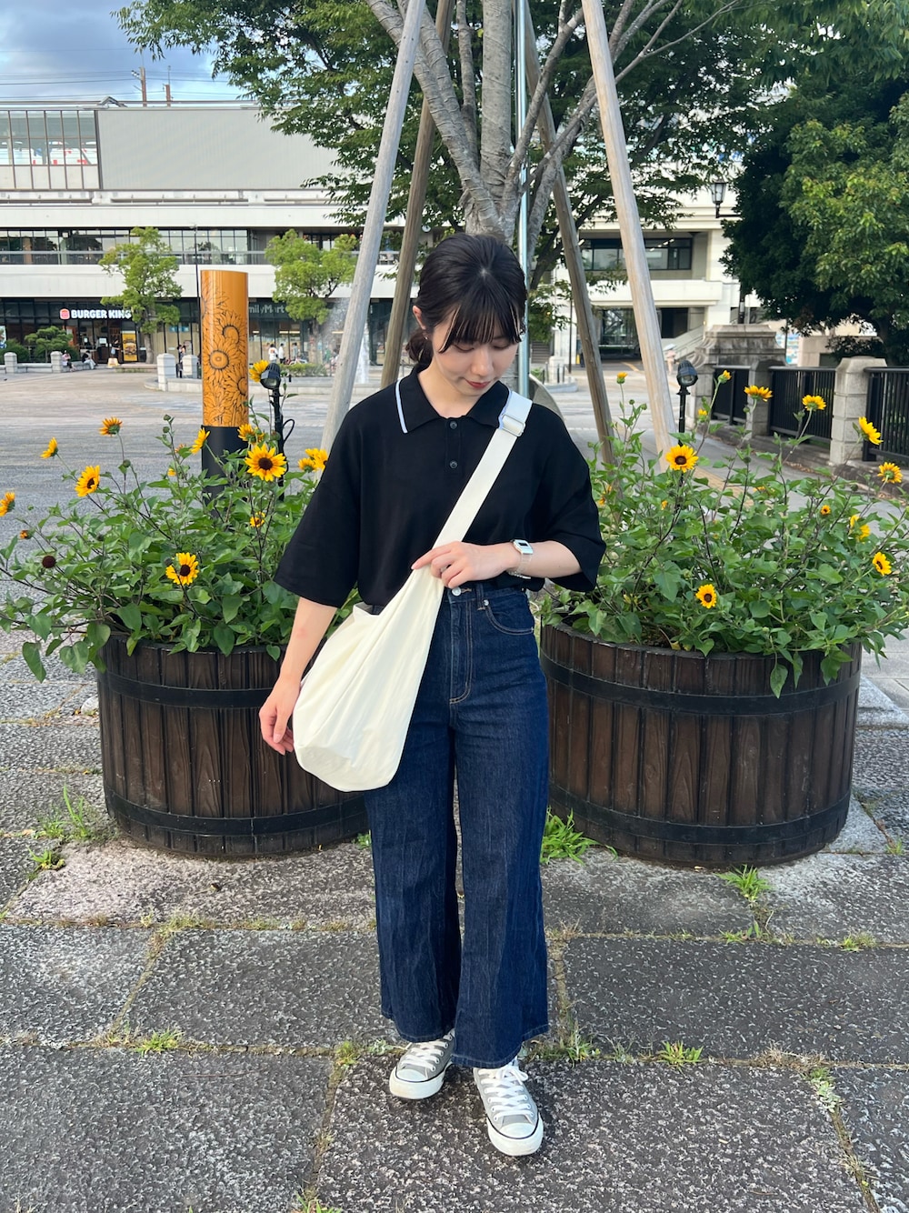 ブルー系のデニムパンツ、ホワイト系のショルダーバッグ、グレー系のスニーカーを着用したレディースの夏コーディネートの1枚目の写真