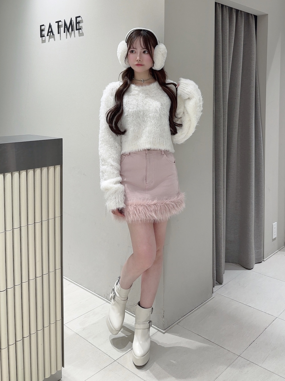 ピンク系のデニムスカート、ホワイト系のニット/セーター、ホワイト系のブーツを着用したレディースの冬コーディネートの1枚目の写真