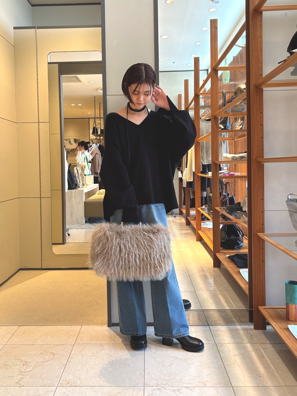 ブラック系のニット/セーター、ベージュ系のショルダーバッグ、ブルー系のデニムパンツを着用したレディースの秋コーディネートの1枚目の写真