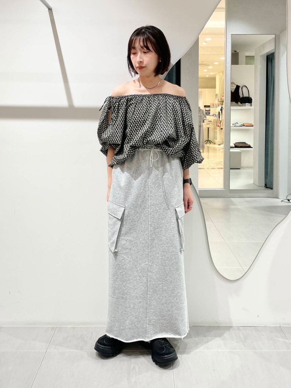 ブラック系のシャツ/ブラウス、グレー系のスカート、ブラック系のスニーカーを着用したレディースの夏コーディネートの1枚目の写真