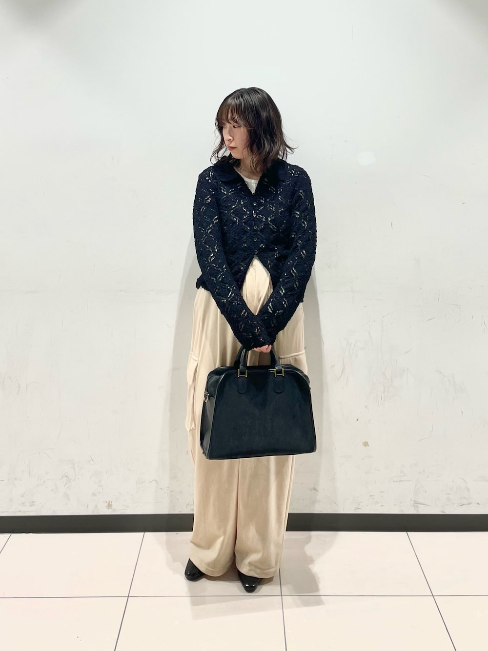 ブラック系のニット/セーター、ベージュ系のその他パンツ、グレー系のボストンバッグを着用したレディースの冬コーディネートの1枚目の写真