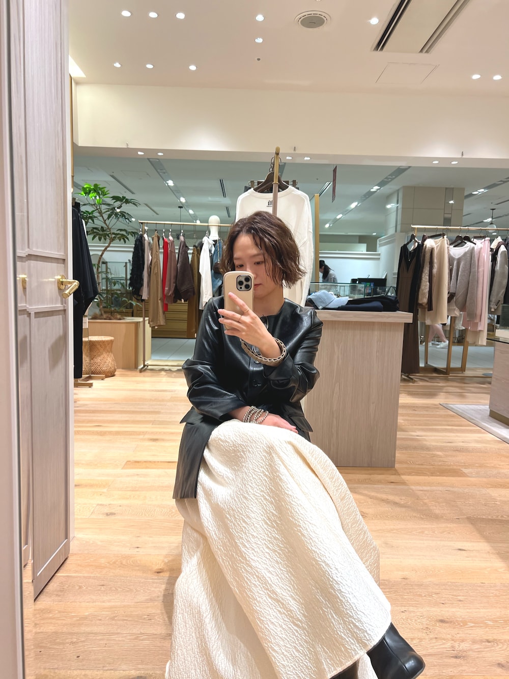 ブラック系のライダースジャケット、ホワイト系のスカート、ブラック系のブーツを着用したレディースの秋コーディネートの1枚目の写真