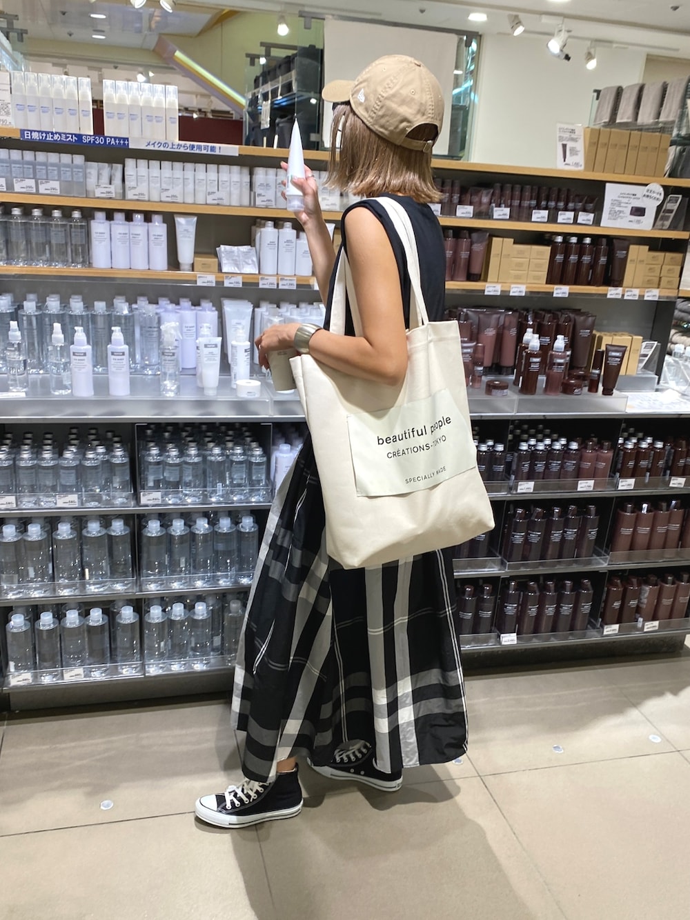 ホワイト系のトートバッグ、ホワイト系のスカート、ブラック系のスニーカーを着用したレディースの夏コーディネートの1枚目の写真