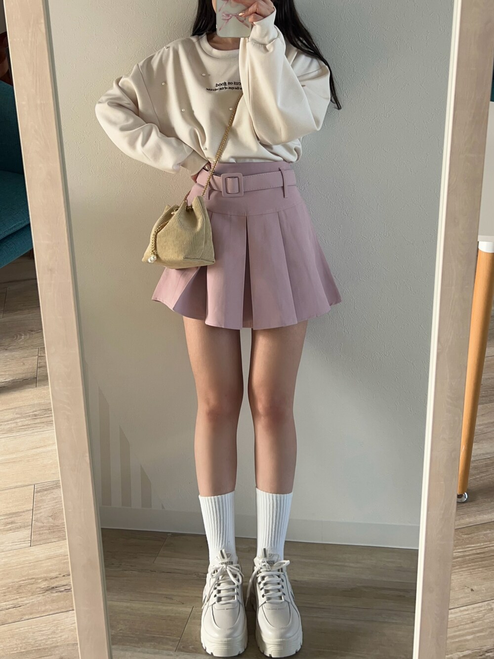 ピンク系のスカート、ベージュ系のショルダーバッグを着用したレディースの冬コーディネートの1枚目の写真