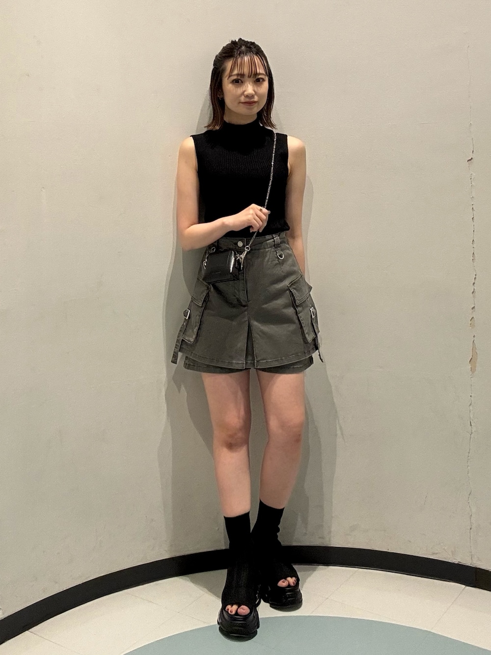 ブラック系のニット/セーター、ブラック系のサンダル、グレー系のスカートを着用したレディースの夏コーディネートの1枚目の写真