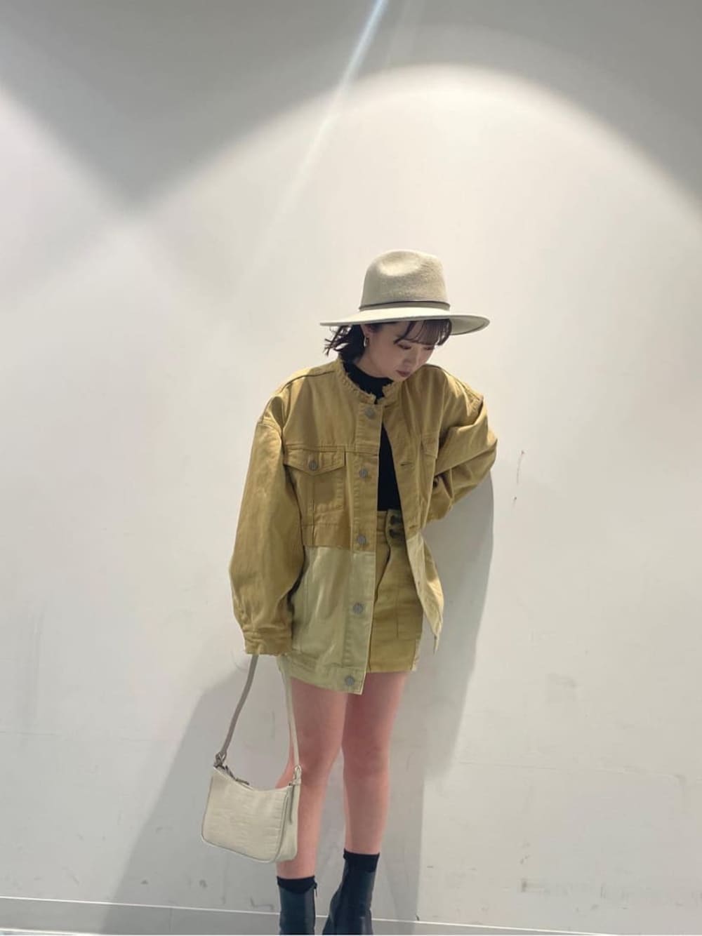 ホワイト系のハンドバッグ、イエロー系のデニムジャケット、イエロー系のスカートを着用したレディースの冬コーディネートの1枚目の写真