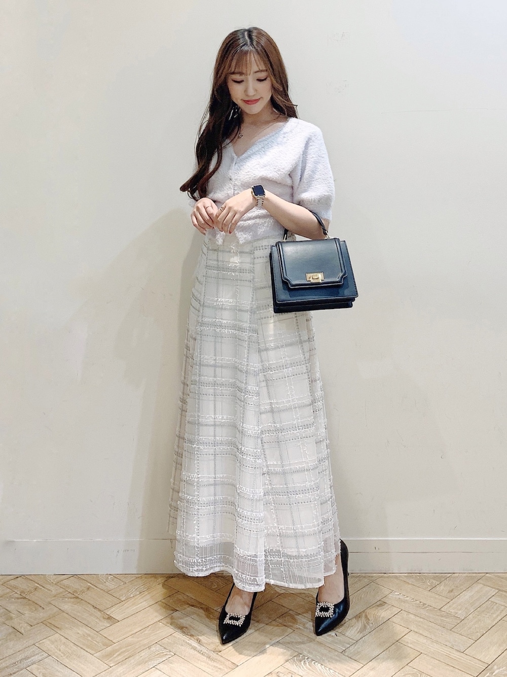 パープル系のカーディガン/ボレロ、ブラック系のスカート、ブラック系のパンプスを着用したレディースの夏コーディネートの1枚目の写真