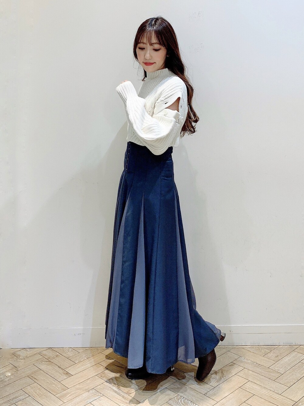 グレー系のスカート、ホワイト系のワンピース、ブラウン系のブーツを着用したレディースの冬コーディネートの1枚目の写真