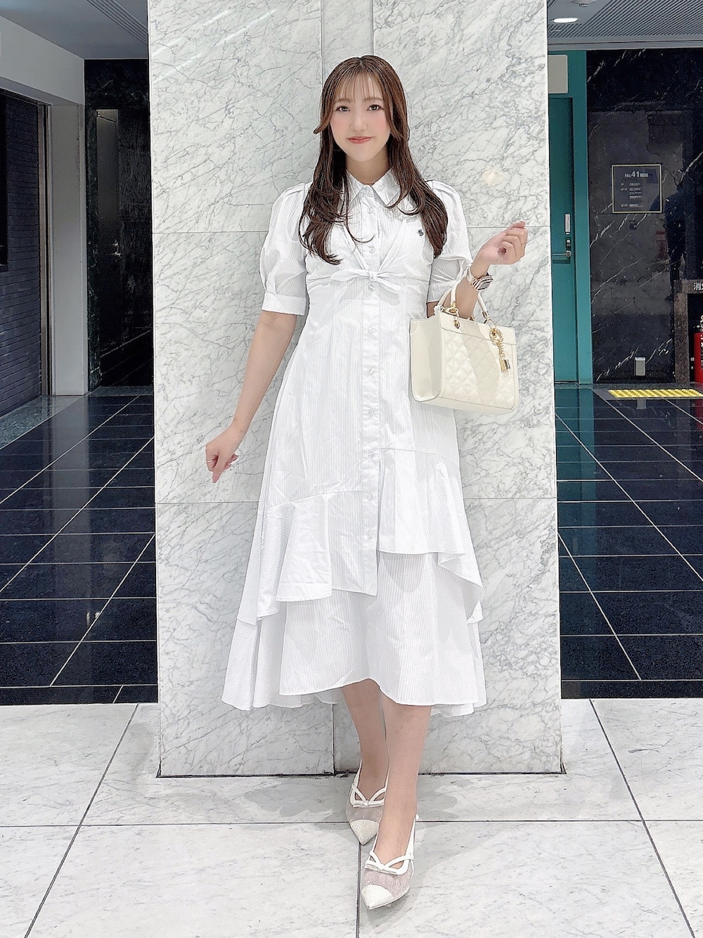 ホワイト系のワンピース、ホワイト系のパンプス、ホワイト系のハンドバッグを着用したレディースの春コーディネートの1枚目の写真