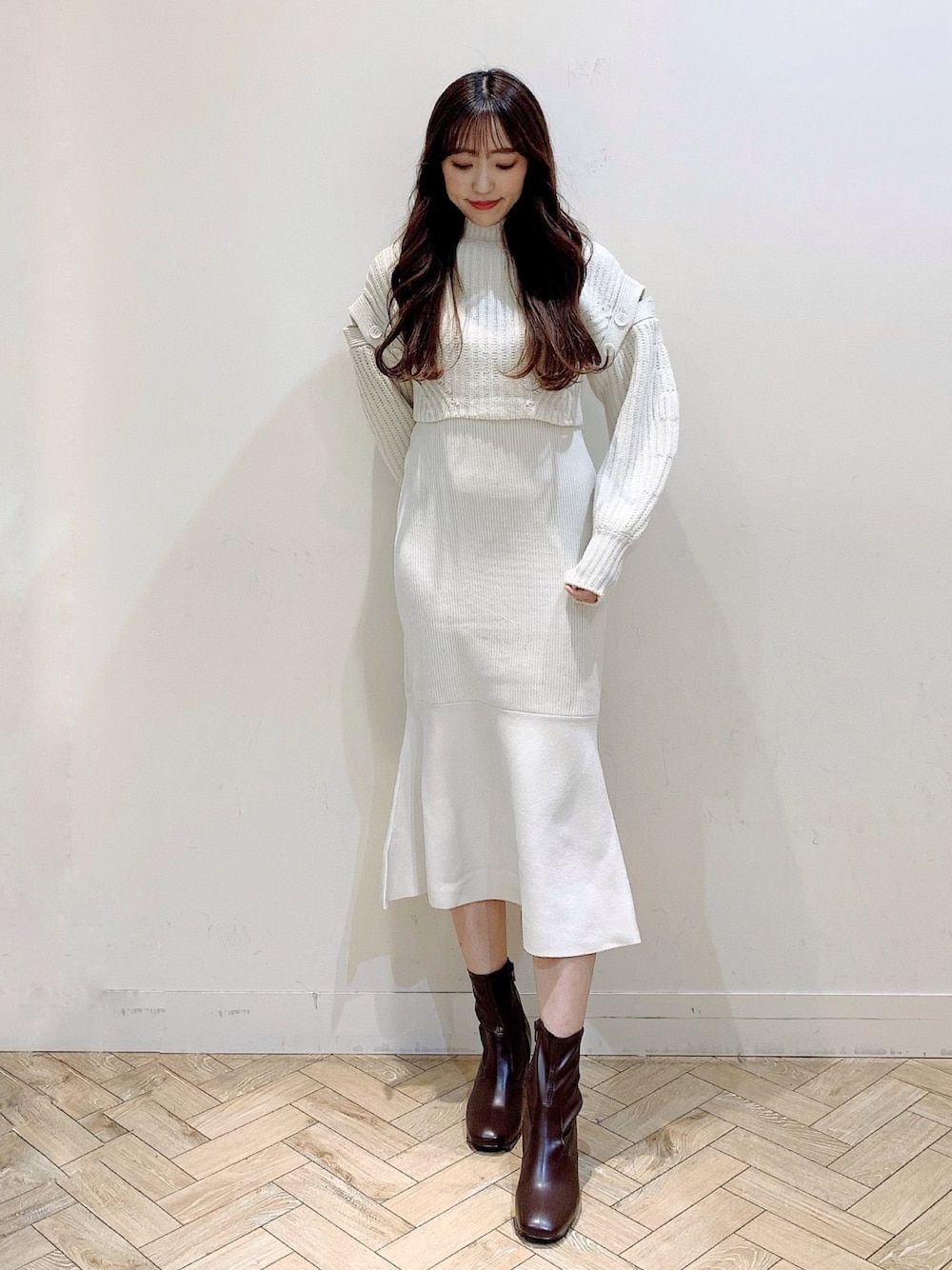 ホワイト系のワンピース、ベージュ系のステンカラーコート、ブラウン系のブーツを着用したレディースの冬コーディネートの1枚目の写真