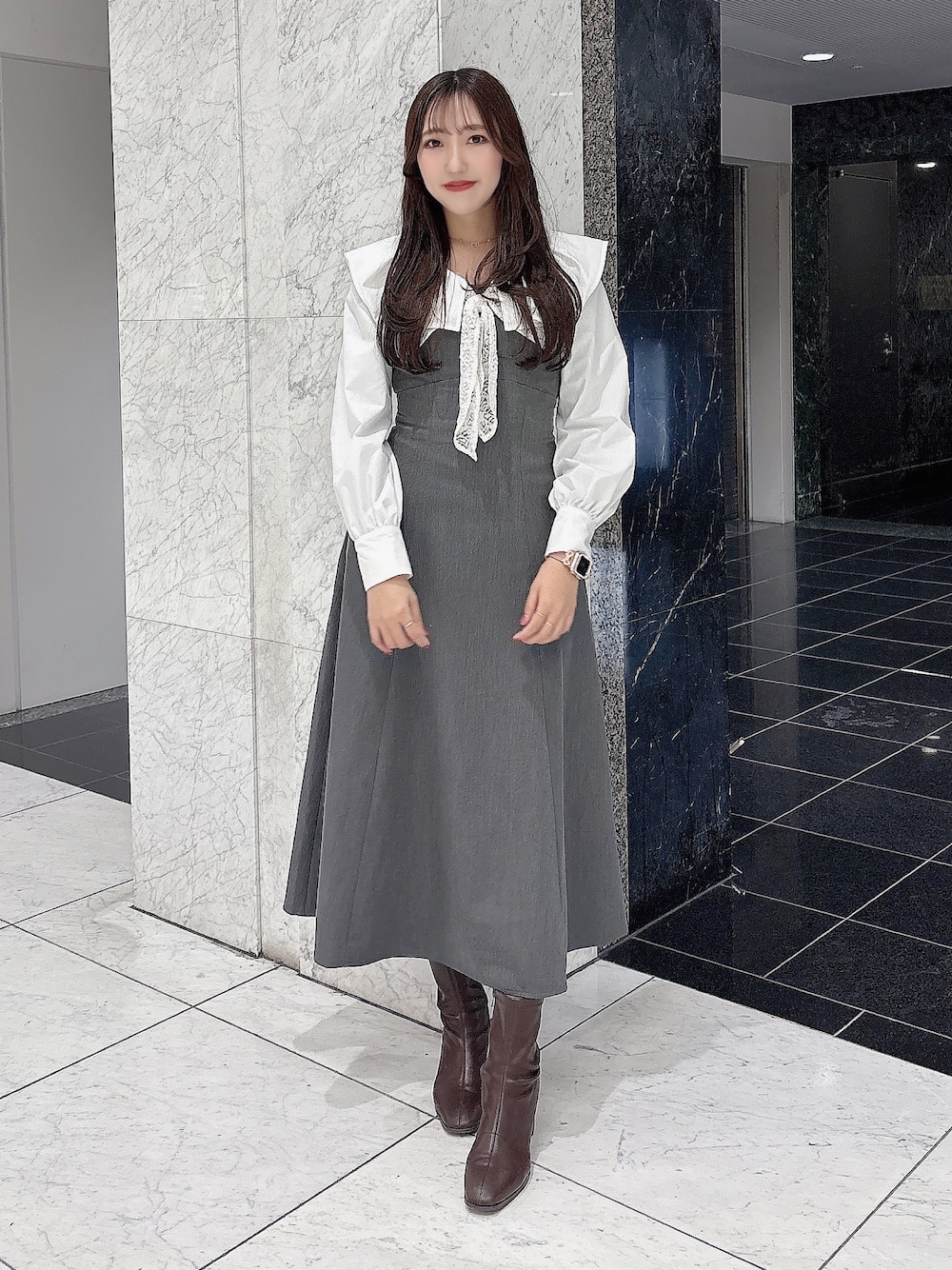 グレー系のワンピース、ブラウン系のブーツを着用したレディースの冬コーディネートの1枚目の写真