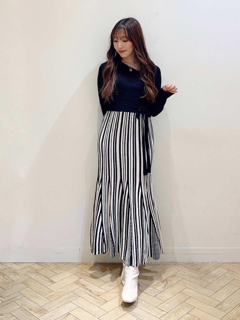 ブラック系のワンピース、ブラック系のダウンジャケット/コート、ホワイト系のブーツを着用したレディースの冬コーディネートの1枚目の写真