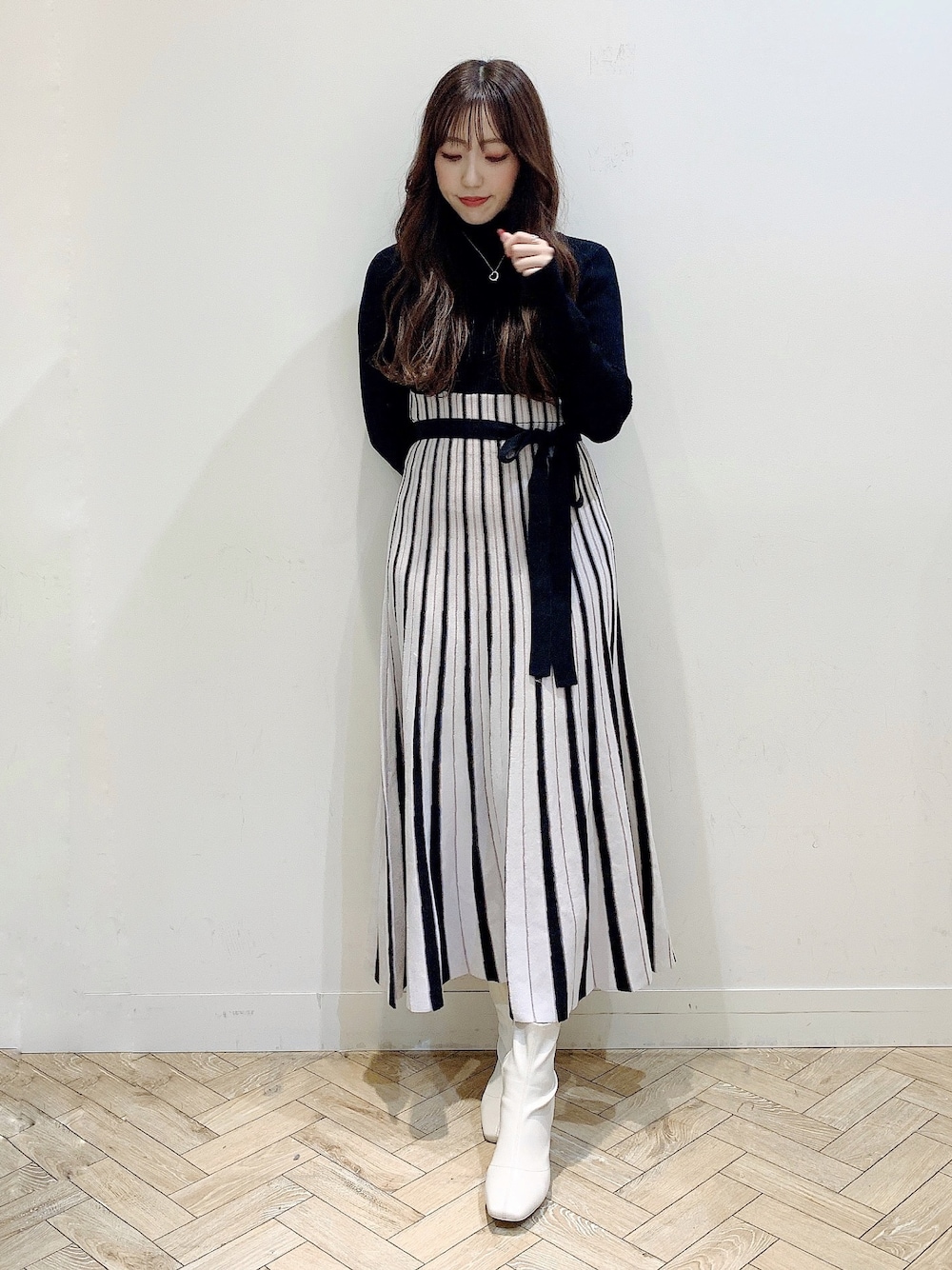 ブラック系のワンピース、ホワイト系のムートンコート、ホワイト系のブーツを着用したレディースの冬コーディネートの1枚目の写真