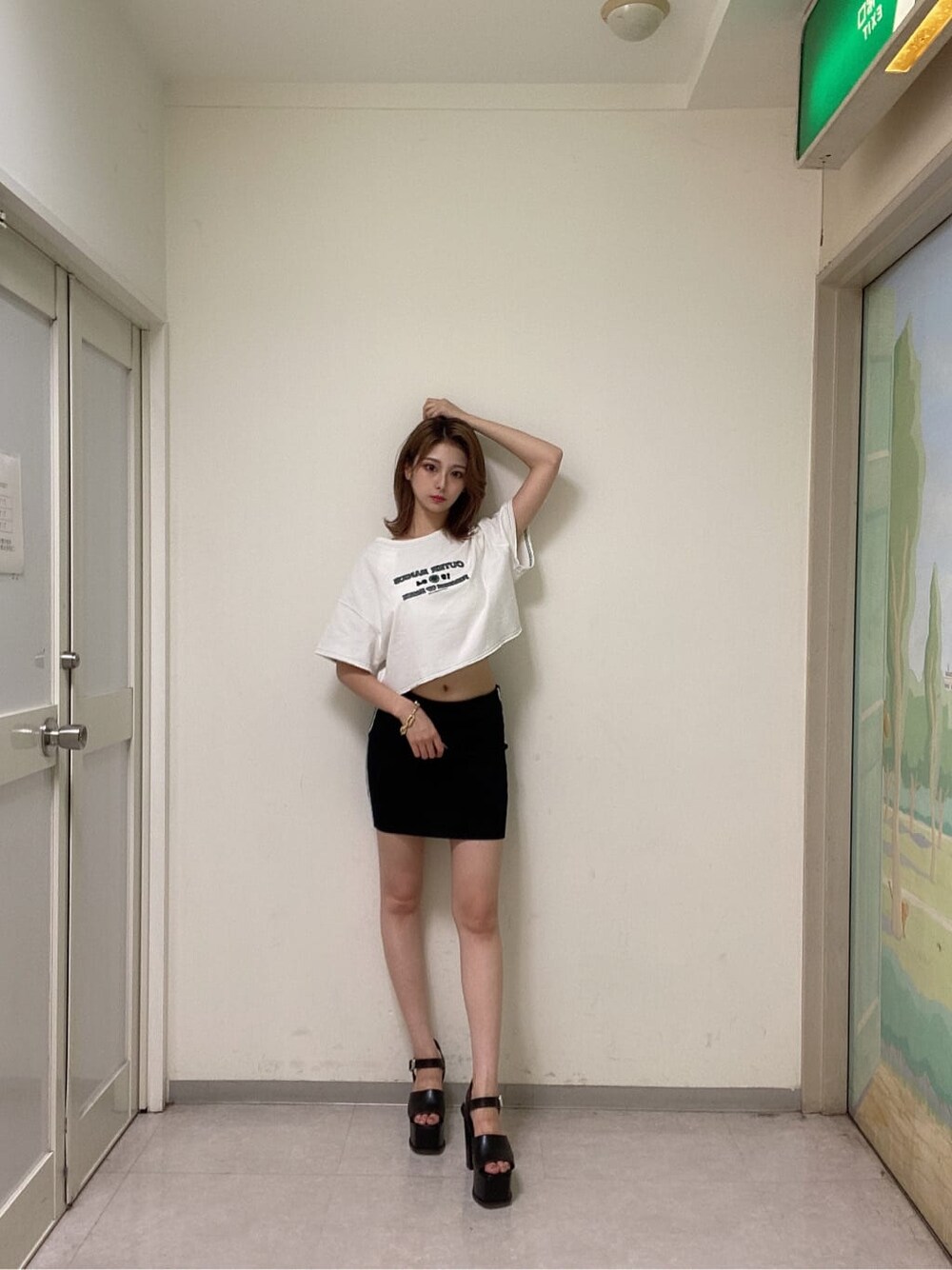 ブラック系のスカート、ブラック系のサンダル、ホワイト系のTシャツ/カットソーを着用したレディースの夏コーディネートの1枚目の写真
