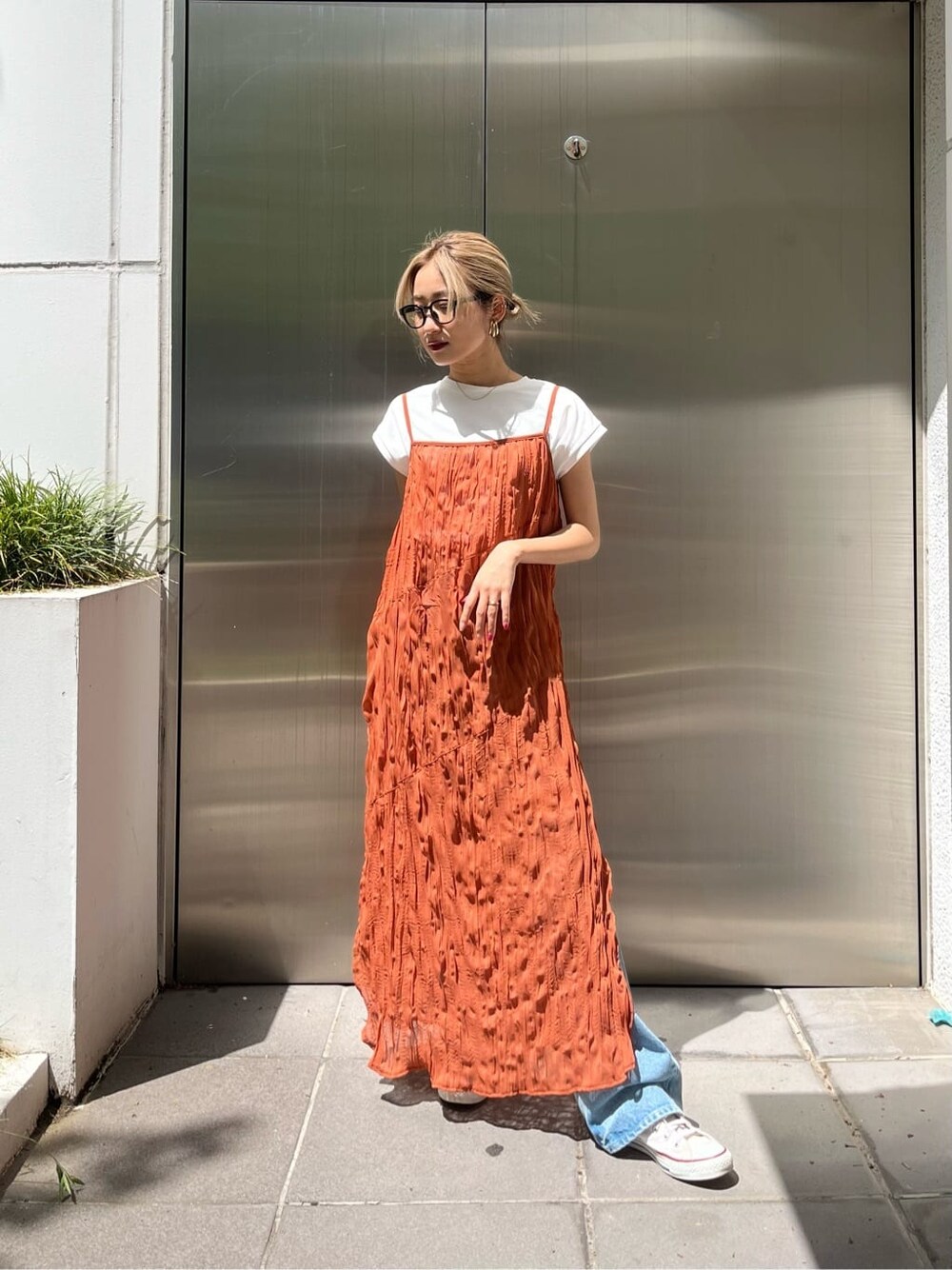 オレンジ系のワンピース、ブルー系のデニムパンツを着用したレディースの春コーディネートの1枚目の写真