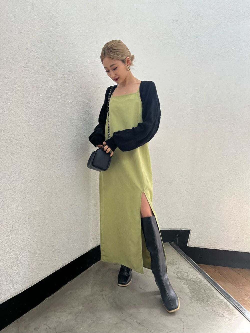 ブラック系のブーツ、ブラック系のニット/セーター、イエロー系のワンピースを着用したレディースの春コーディネートの1枚目の写真