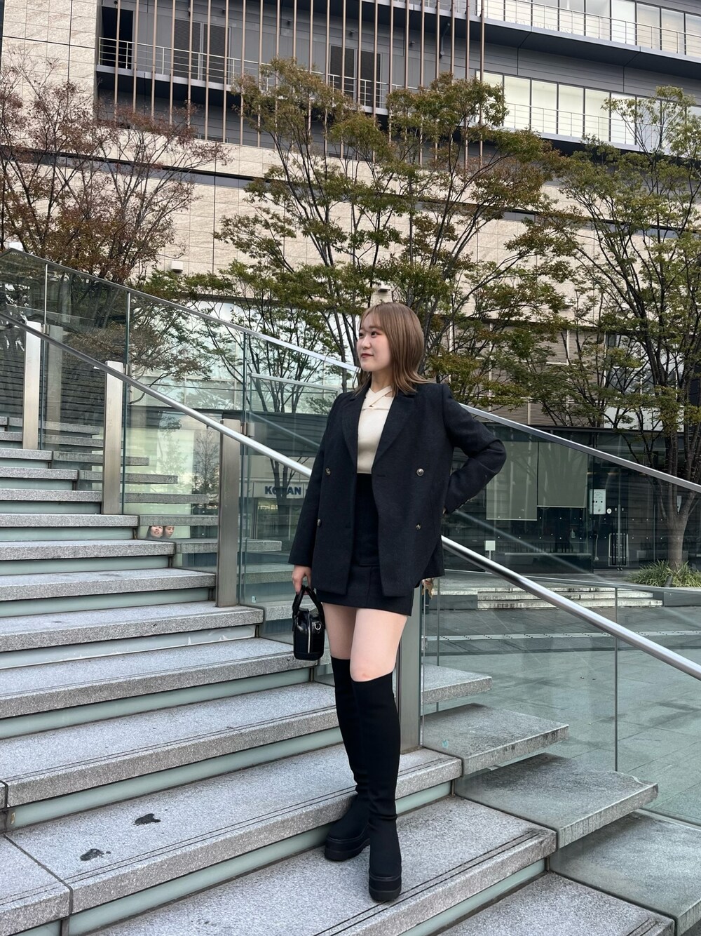 グレー系のテーラードジャケット、ホワイト系のニット/セーター、グレー系のスカートを着用したレディースの秋コーディネートの1枚目の写真