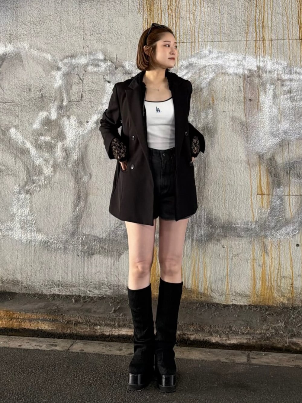 ブラック系のテーラードジャケット、ブラック系のパーカー、ホワイト系のキャミソールを着用したレディースの春コーディネートの1枚目の写真