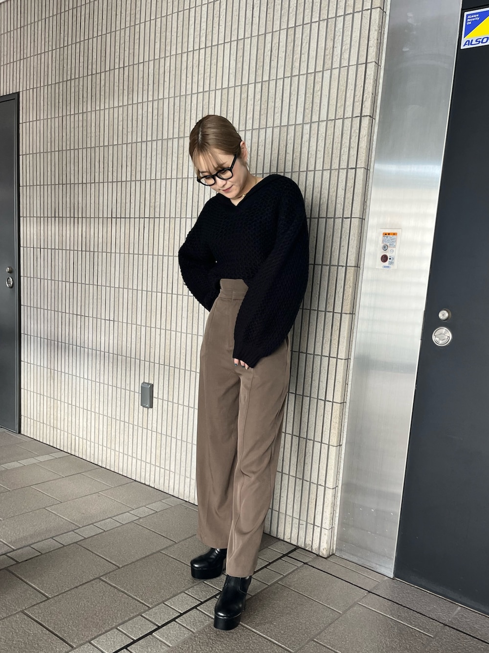 ブラック系のニット/セーター、ベージュ系のスラックス、ブラック系のブーツを着用したレディースの冬コーディネートの1枚目の写真