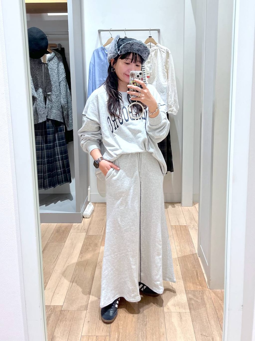 グレー系のスウェット、グレー系のスカート、ブラック系のキャップを着用したレディースの秋コーディネートの1枚目の写真